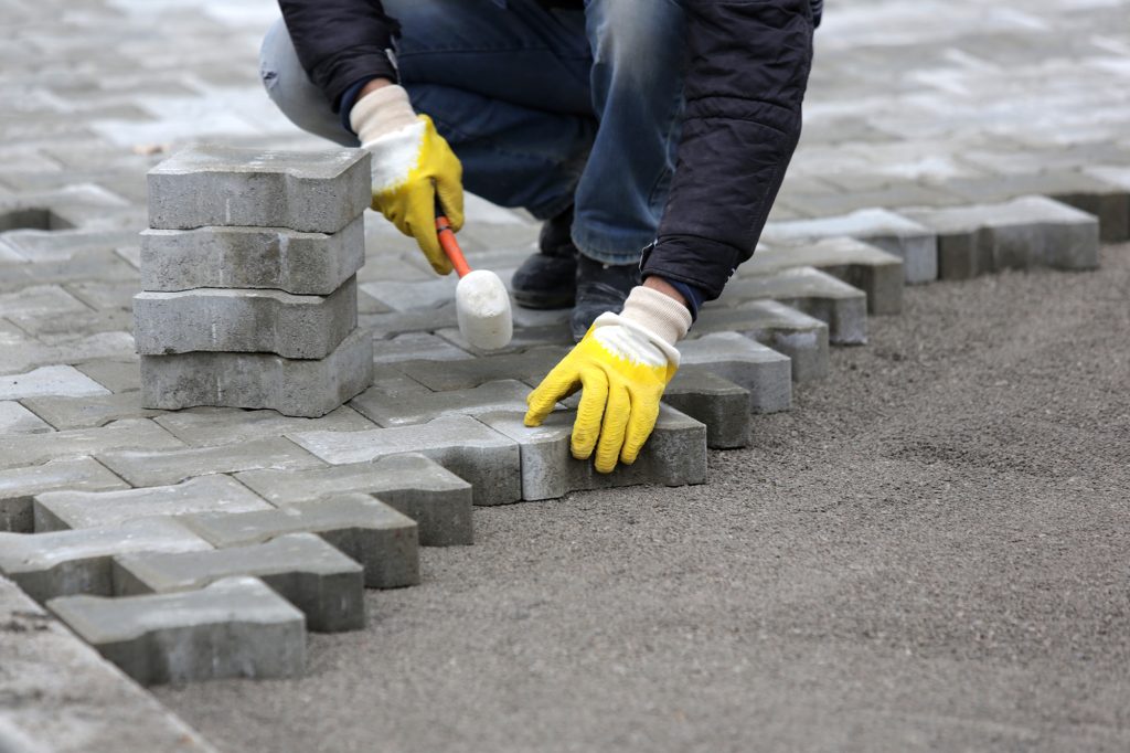 Paving stone worker is putting down pavers during a construction of a city street.
